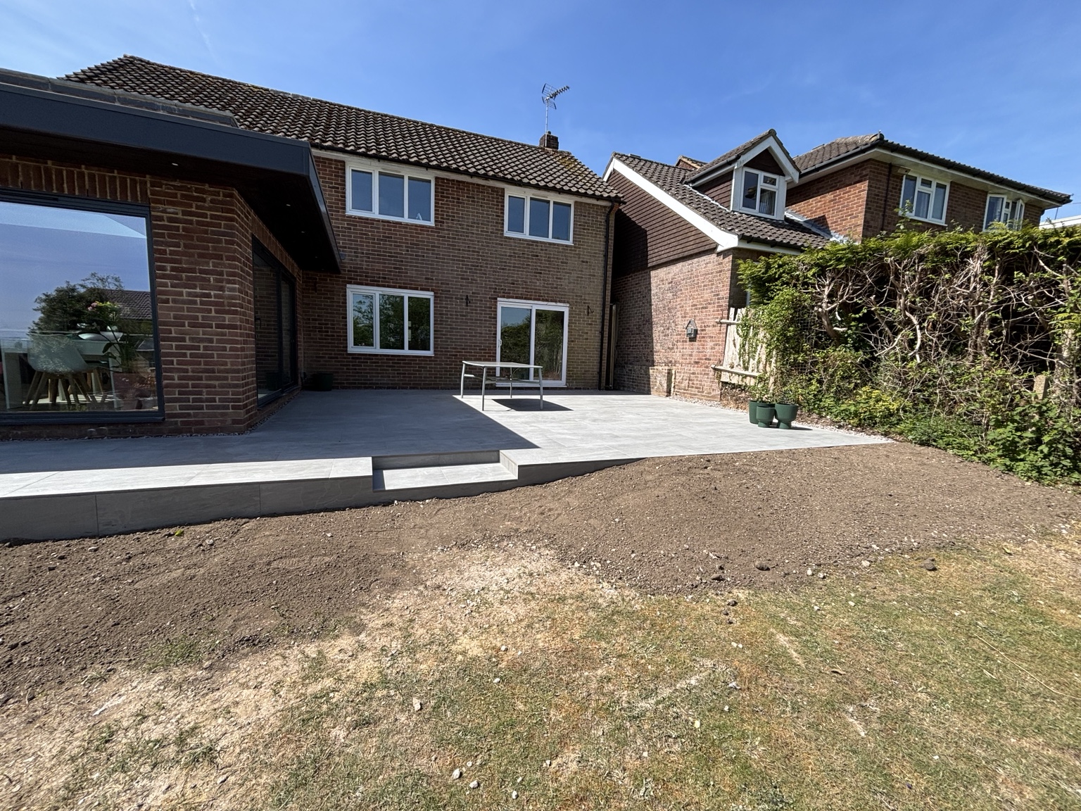 Completed paved patio with steps beside the house